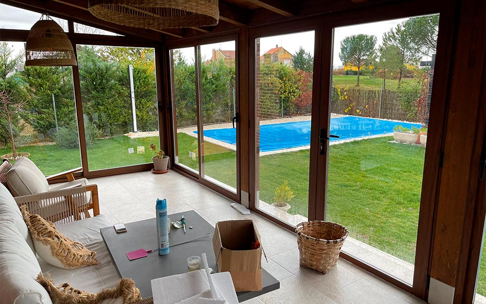 Porche cerrado con carpintería de aluminio o PVC con acabado madera con vistas al jardín con piscina, en Valladolid